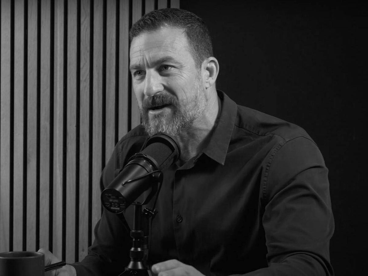 Andrew Huberman hablando ante un micrófono de pódcast, en blanco y negro, junto a su cita sobre el descanso