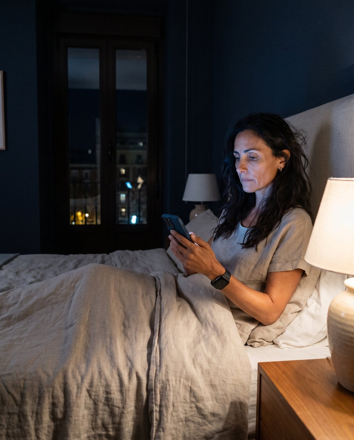 Mujer de unos 45 años despierta en la cama de madrugada mirando el móvil